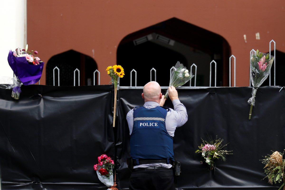A police officer places flowers at the entrance of Masjid Al Noor mosque in Christchurch, New Zealand, on March 17, 2019. (Jorge Silva/Reuters)