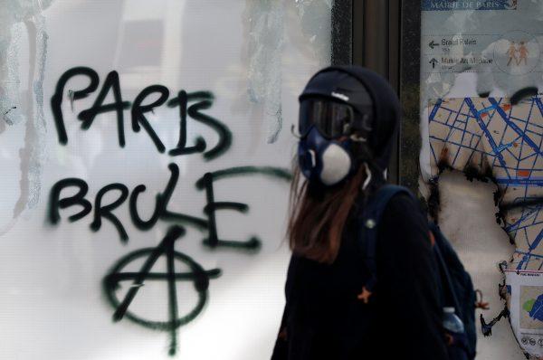 A protester walks past graffiti reading 'Paris burns' during a demonstration by the yellow vests movement in Paris on March 16, 2019. (Benoit Tessier/Reuters)