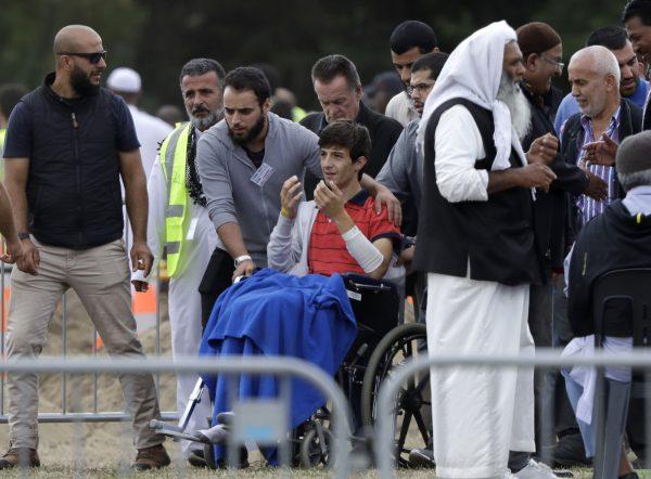Zaed Mustafa, in a wheelchair, brother of Hamza and son of Khalid Mustafa killed in the March 15 mosque shootings reacts during the burial at the Memorial Park Cemetery in Christchurch, New Zealand, on March 20, 2019. (AP Photo/Mark Baker)