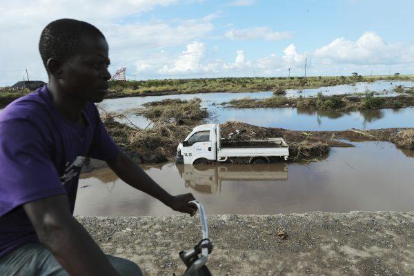 A man cycles past a truck swept away by Cyclone Idai in Nyamatanda,  Mozambique, on March 21, 2019. (Tsvangirayi Mukwazhi/AP Photo)