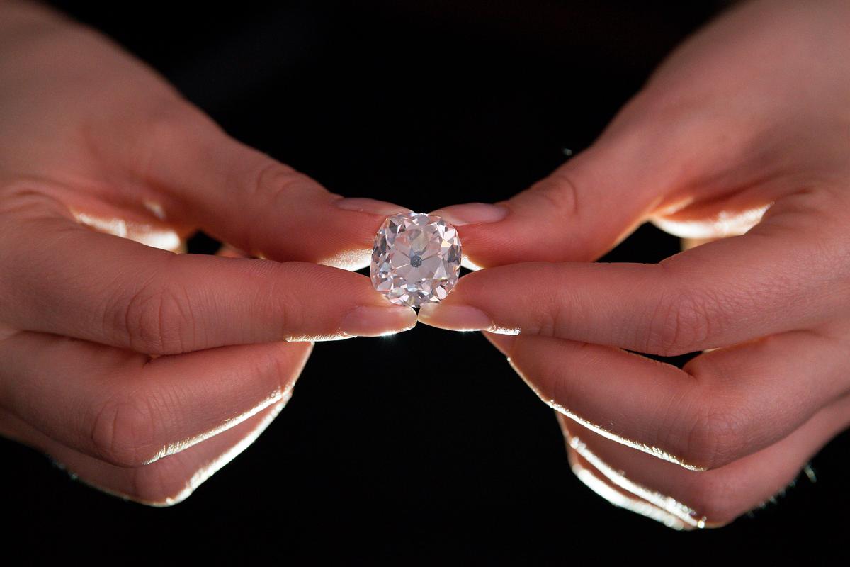 The 26.27-carat cushion-shaped white diamond for sale at Sotheby's auction house in London was expected to fetch around US$456,000 at auction 30 years after its owner paid 10 pounds for it at a car boot sale, thinking it was a costume jewel. (©Getty Images | <a href="https://www.gettyimages.com/detail/news-photo/member-of-sothebys-staff-poses-holding-a-26-27-carat-news-photo/686760210">JUSTIN TALLIS/AFP</a>)