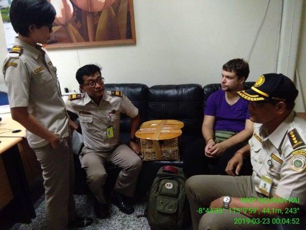 Andrei Zhestkov sits with customs officials in Indonesia with the rattan box used to transport the orangutan on March 23. (Karantina Denpasar)