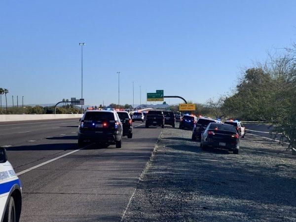Police vehicles parked next to the scene of a crime, in which a white Lexus sedan that traveled off the Loop 101, through the dry canal embankment and collided with the right-of-way fence in Peoria, Ariz., on March 22, 2019. (Arizona Department of Public Safety via AP)