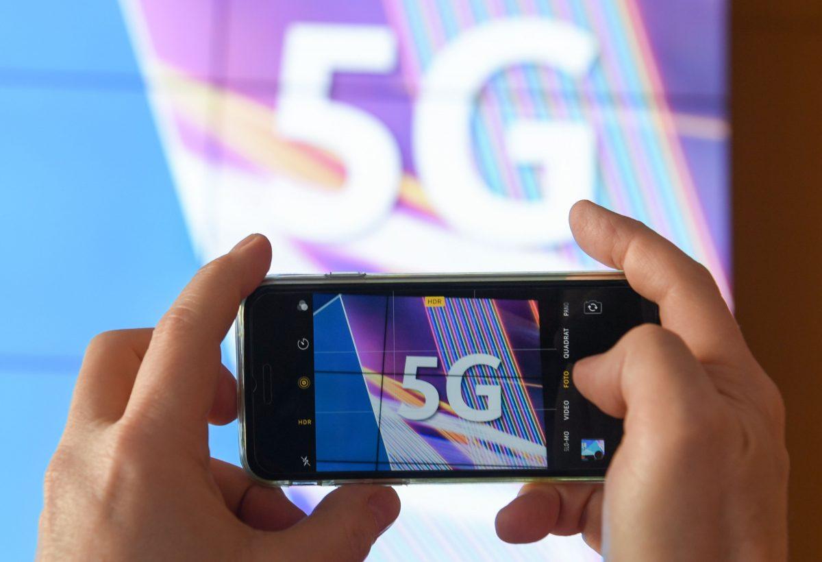 A journalist takes pictures of a projection screen prior to the start of Germany's auction for the construction of an ultra-fast 5G mobile network on March 19, 2019 at the German Federal Network Agency in Mainz, western Germany. (Arne Dedert/AFP/Getty Images)