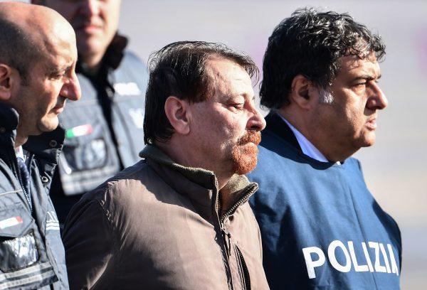 Italian communist militant Cesare Battisti is escorted by police officers after stepping off a plane coming from Bolivia in Rome on Jan. 14, 2019. (Alberto Pizzoli/AFP/Getty Images)