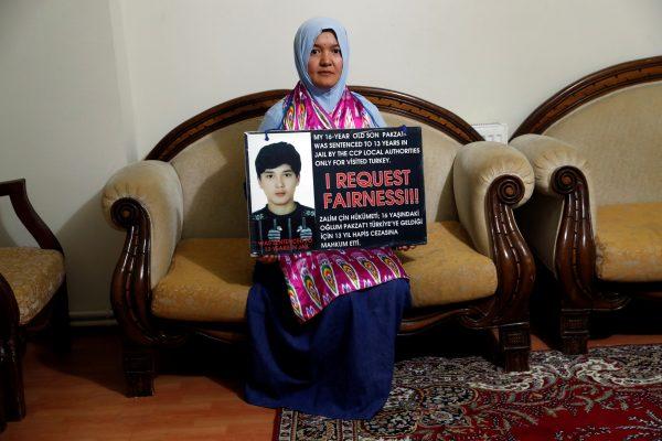 Gulgine Mahmut holds a placard with a picture of her son Pakzat at her home in Istanbul, Turkey on Dec. 12, 2018. (Murad Sezer/Reuters)