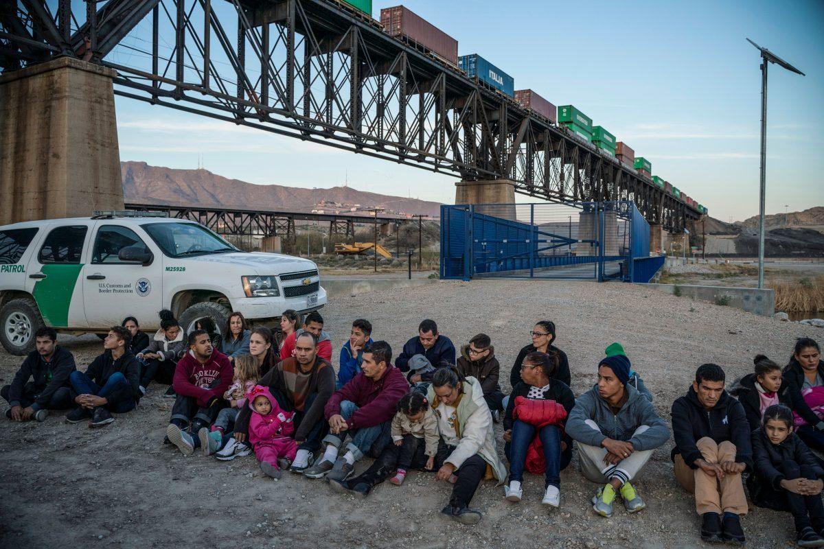 A group of about 30 illegal immigrants from Brazil sit on the ground near Border Patrol agents, on the property of Jeff Allen, on the U.S.–Mexico border in Sunland Park, New Mexico, on March 20, 2019. (Paul Ratje/AFP/Getty Images)