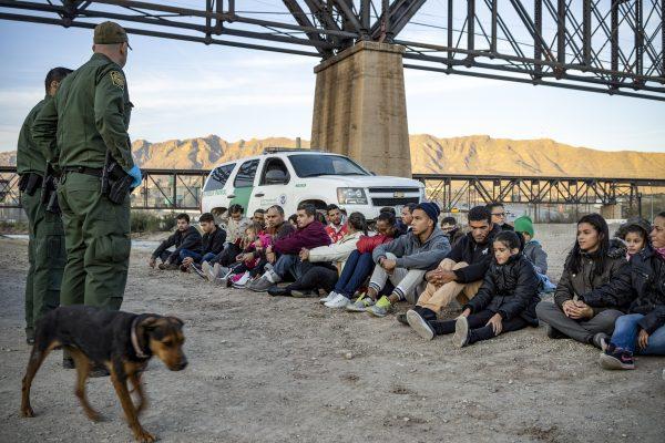 A group of about 30 illegal immigrants from Brazil, sit on the ground near Border Patrol agents on the property of Jeff Allen, by the U.S.–Mexico border in Sunland Park, New Mexico, on March 20, 2019. (Paul Ratje/AFP/Getty Images)