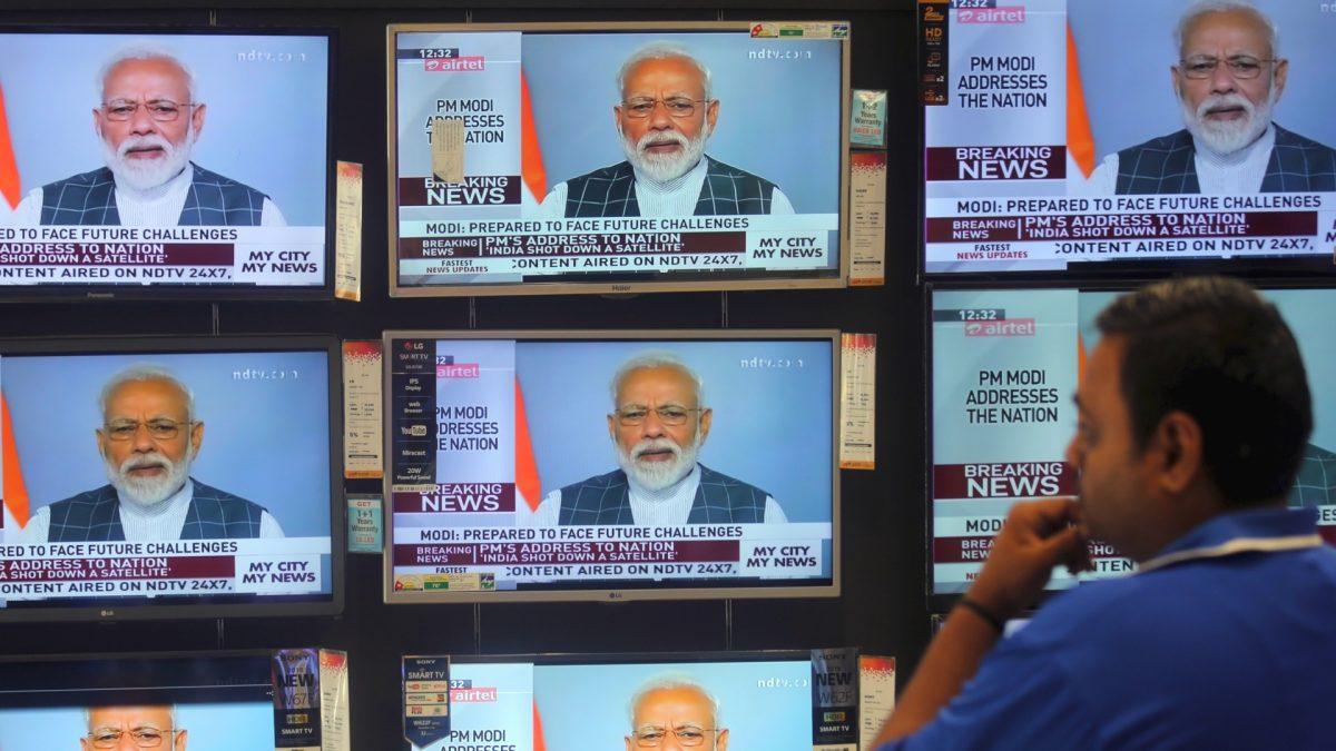 A man watches Prime Minister Narendra Modi addressing to the nation, on TV screens inside a showroom in Mumbai, India, on March 27, 2019. (Francis Mascarenhas/Reuters)