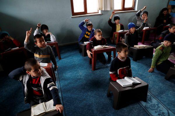 Uyghur boys who have lost at least one parent, raise their hands during a Koran class in a madrasa, or religious school, in Kayseri, Turkey on Jan. 31, 2019. (Murad Sezer/Reuters)