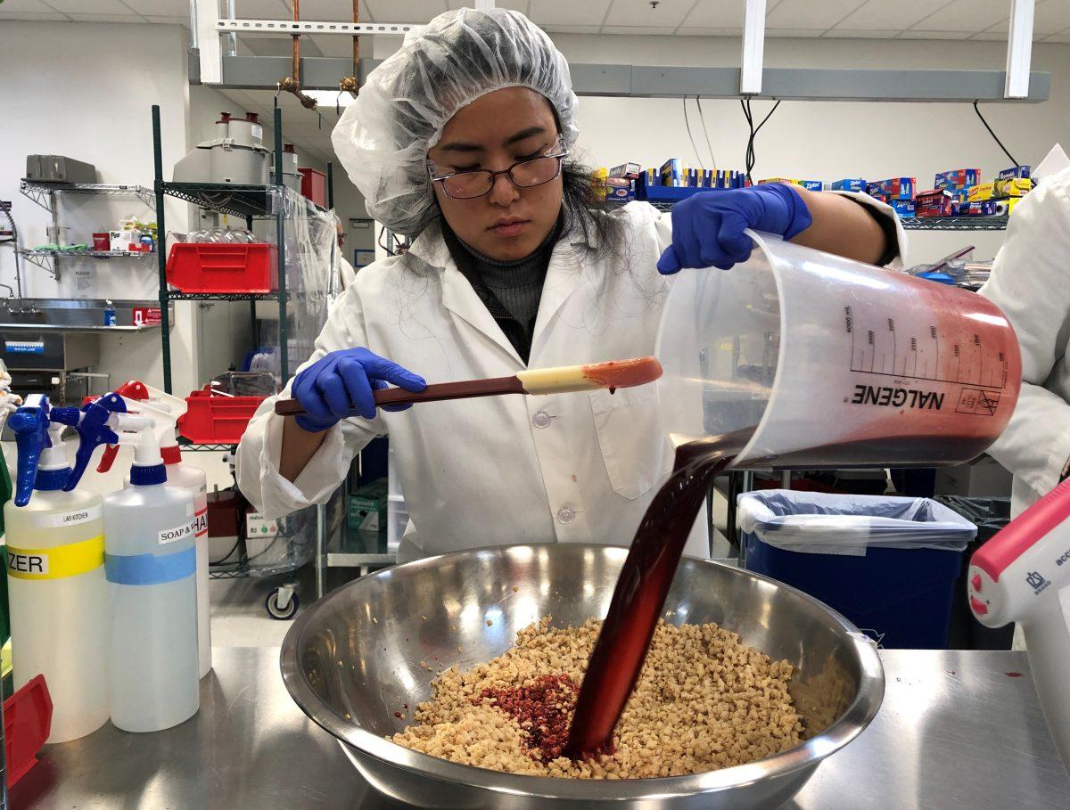 Impossible Foods research technician Alexia Yue pours ingredients into a plant-based mixture for burgers at their facility in Redwood City, Calif., on March 26, 2019. (Jane Lanhee Lee/Reuters)