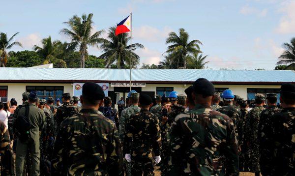A Philippine flag flutters on the Philippine-occupied Thitu island, located in the disputed South China Sea, as soldiers and civilians sing the country's national anthem on April 21, 2017. (Erik De Castro/Reuters)