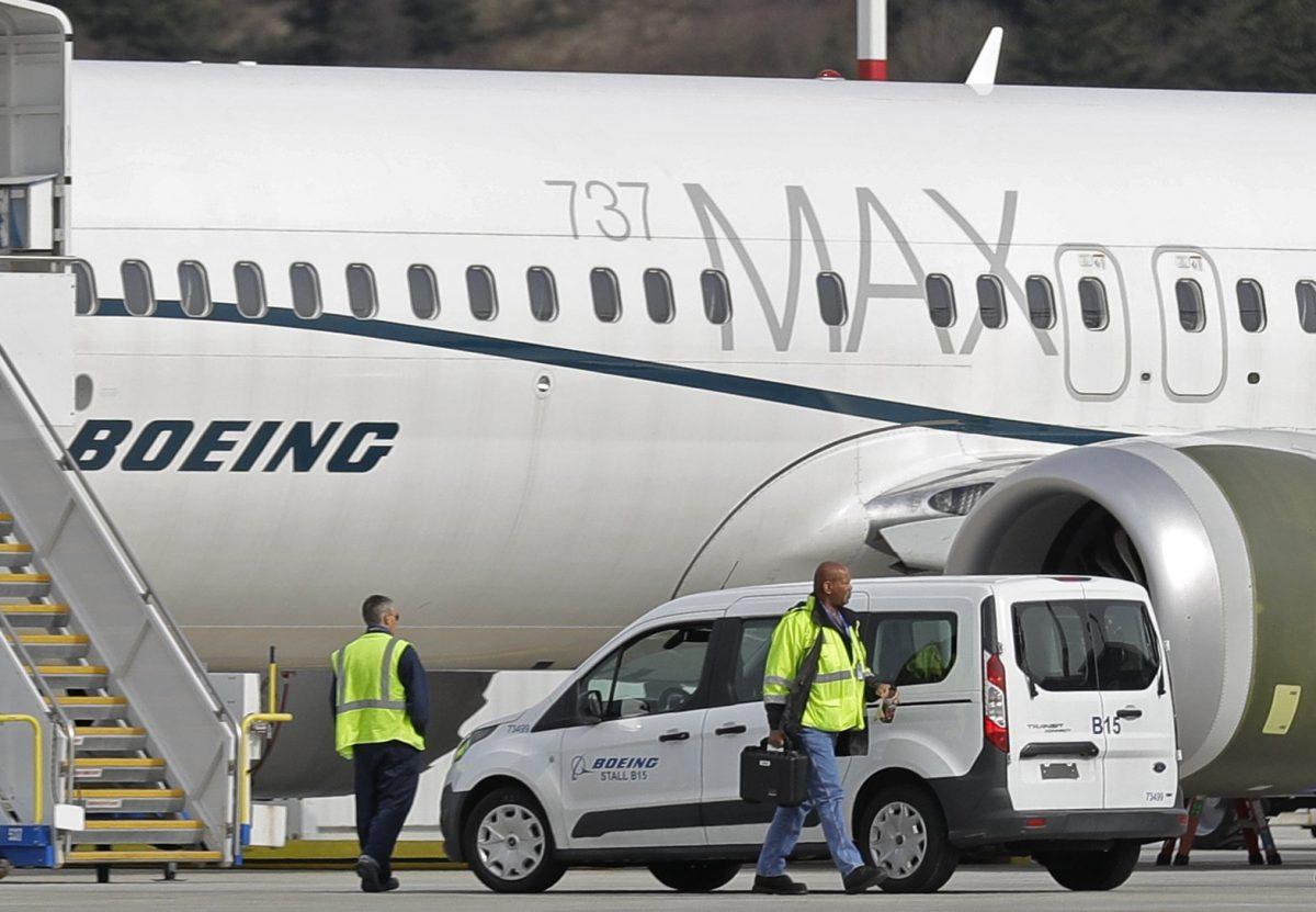 Workers walk next to a Boeing 737 MAX 8 airplane parked at Boeing Field, in Seattle, on March 14, 2019. (Ted S. Warren/File via AP)