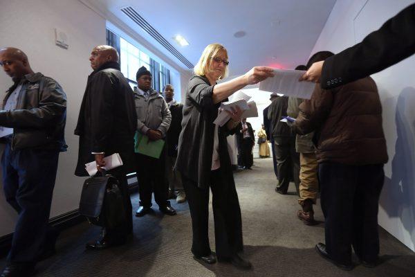Job fair employee Arleen Greco hands out surveys as applicants wait in line line up to meet potential employers at the Diversity Job Fair in Manhattan, N.Y. on Dec. 6, 2012. (John Moore/Getty Images)