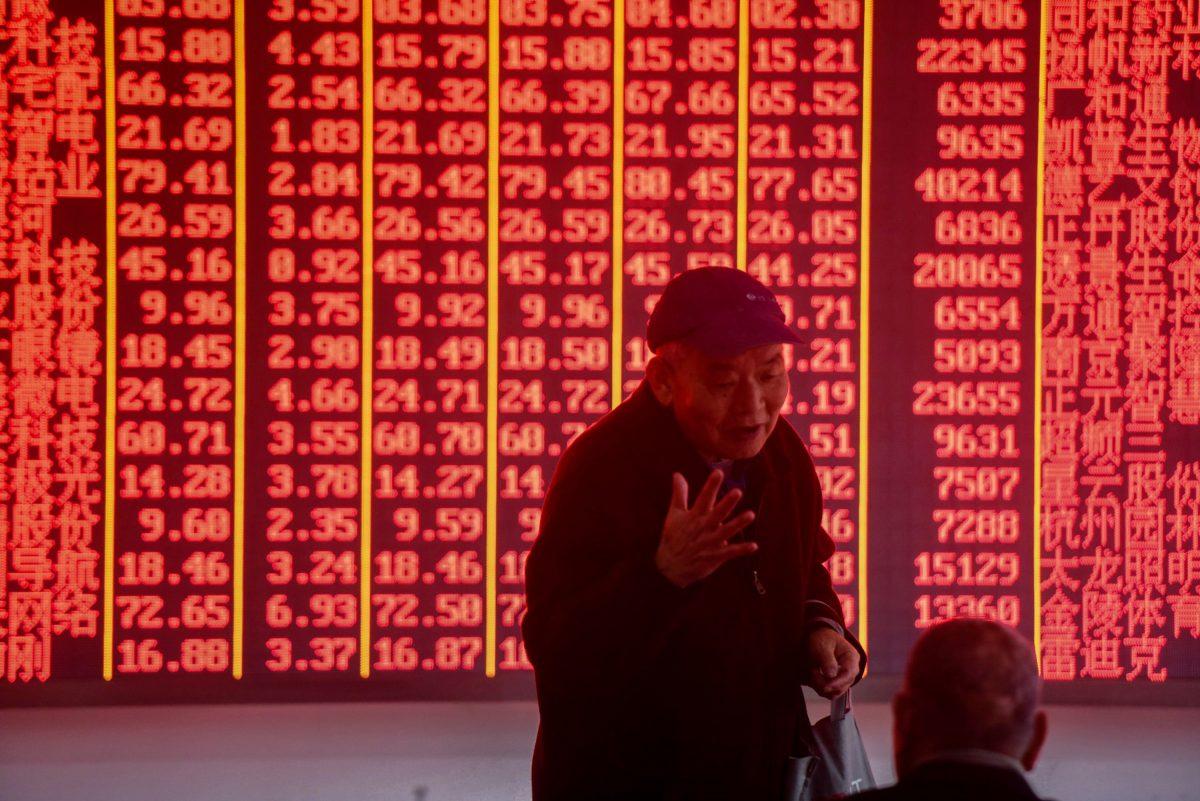 Investors talk in front of an electronic board showing stock information at a securities company in Hangzhou in eastern China's Zhejiang Province on Dec. 3, 2018. (STR/AFP/Getty Images)