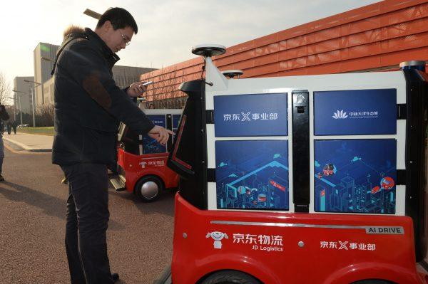 A man picks up a package from driverless delivery vehicle for Chinese e-commerce company JD.com during a test operation at the Sino-Singapore Tianjin Eco-City in Tianjin on Jan. 18, 2018. The vehicles fully charged can run up to 18 miles and can carry loads up to 330 lbs. in weight. (-/AFP/Getty Images)