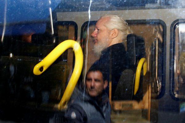 A man is reflected in a window of a police van as WikiLeaks founder Julian Assange is seen inside, after he was arrested, in London on April 11, 2019. (Henry Nicholls/Reuters)