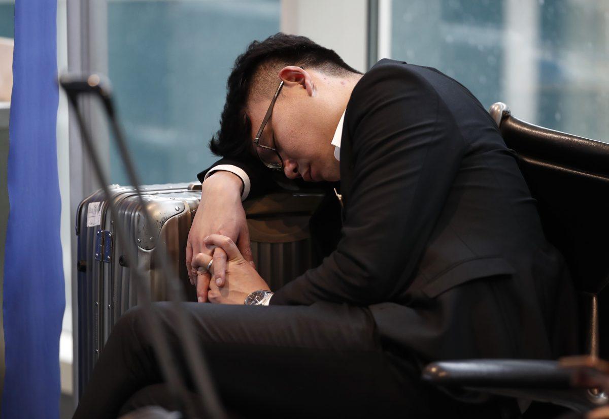 A passenger sleeps on his luggage in Denver International Airport in Denver, on April 10, 2019. (David Zalubowski/AP Photo)