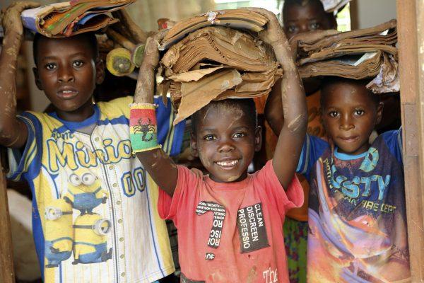 Children carry books damaged by the cyclone at a camp for displaced survivors of cyclone Idai in Dombe, about 280km west of Beira, Mozambique, on April 4, 2019. (Tsvangirayi Mukwazhi/Photo via AP)