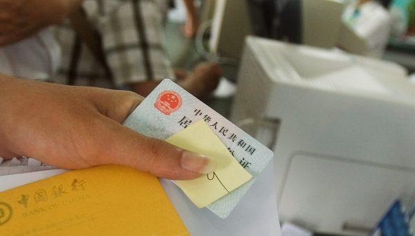 A Chinese citizen shows his ID card and bank book at a branch of the Bank of China in Sanya City, Hainan Province, China, on May 5, 2008. (Feng Li/Getty Images)