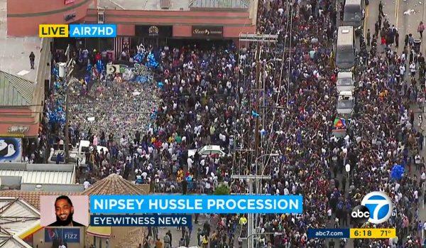 Thousands of people around the memorial and shrine where rapper Nipsey Hussle was shot and killed, as a hearse carrying his body drives by in South Los Angeles on April 11, 2019. (Screenshot/ABC7 via AP)
