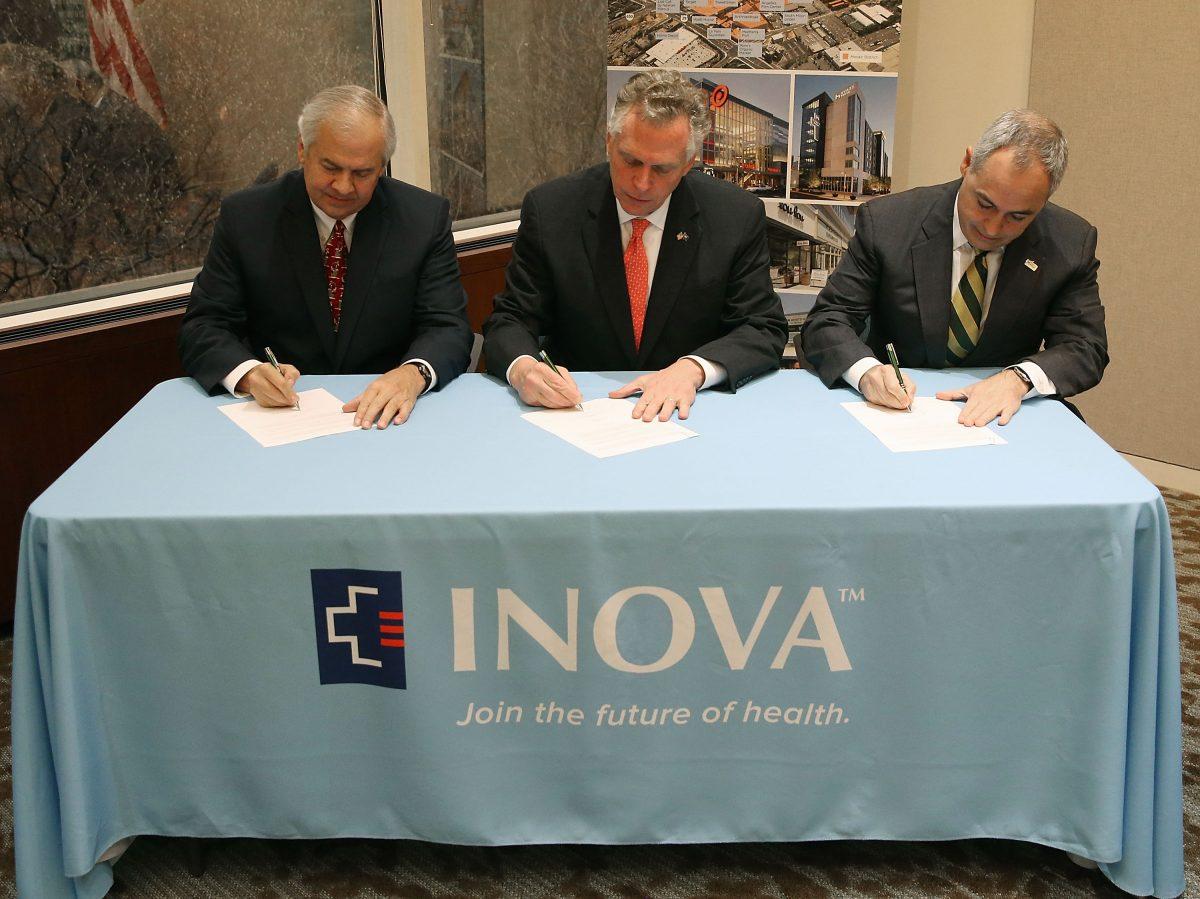 Angel Cabrera, right, president of George Mason University, signs a partnership agreement with Gov. Terry McAuliffe (D-Va.), center, and J. Knox Singleton, CEO of INOVA, in a Dec. 22, 2015 file photo. (Mark Wilson/Getty Images)