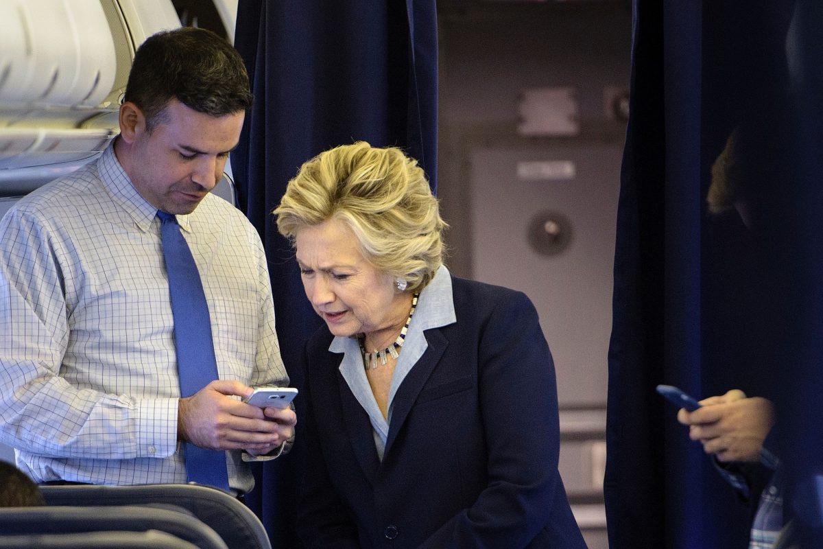 Hillary Clinton looks at a smartphone with national press secretary Brian Fallon on her plane at Westchester County Airport in White Plains, New York, on Oct. 3, 2016. (Brendan SmialowskiAFP/Getty Images)
