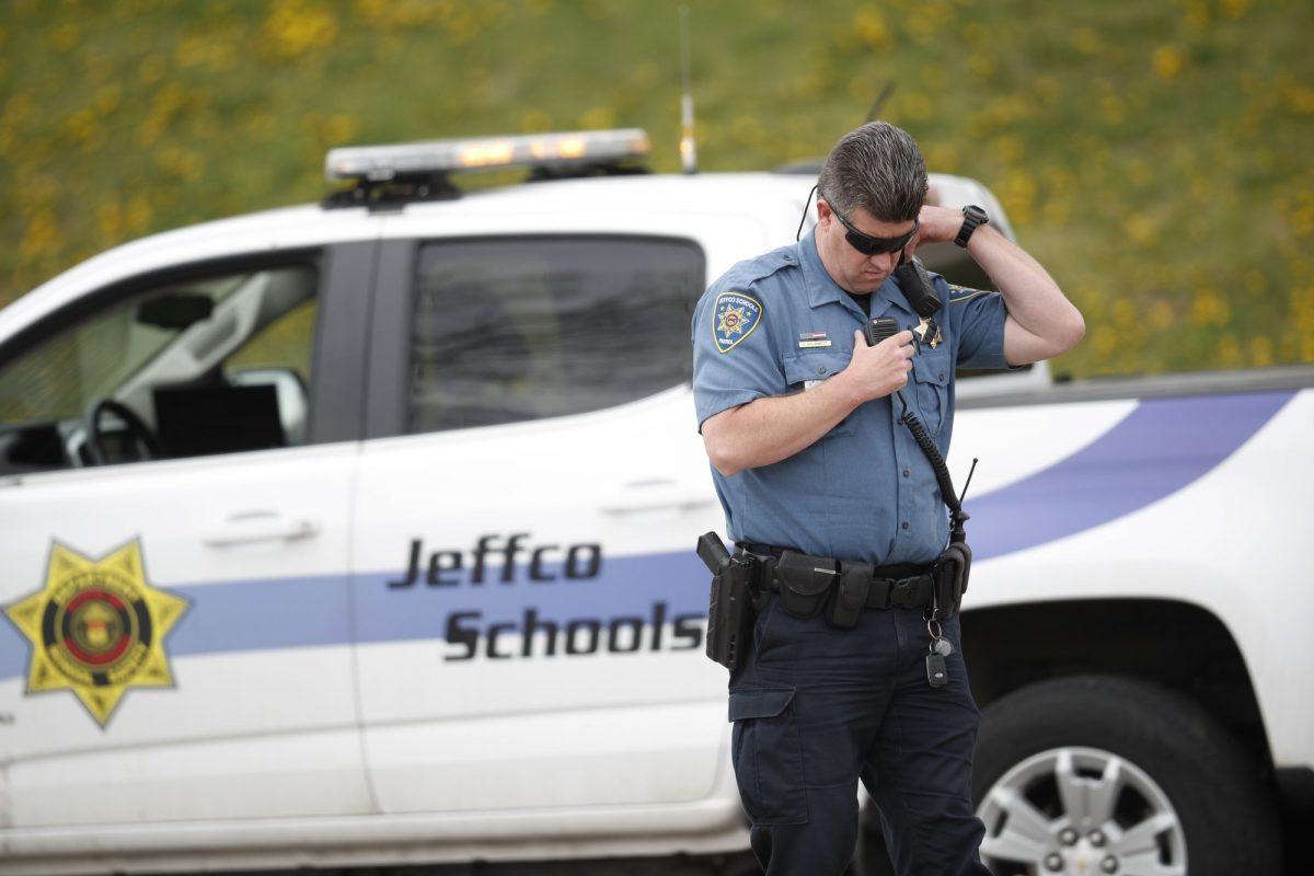An officer from Jefferson County, Colo., Schools listens on his radio as students leave Columbine High School in Littleton, Colo., on April 16, 2019. (David Zalubowski/Photo via AP)