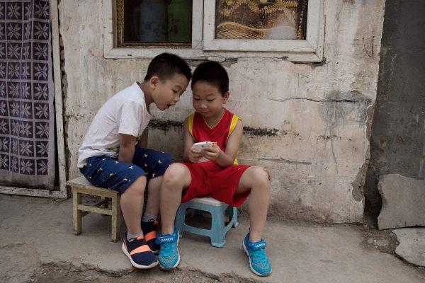 Two Chinese boys use a smartphone outside their home in Beijing in June 2016. (Nicolas Asfouri/AFP/Getty Images)