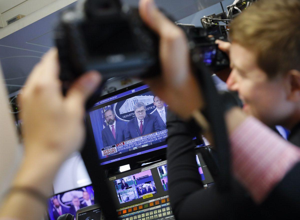Journalists take photographs of the television broadcast monitors in the press room of the White House in Washington of Attorney General William Barr speaking alongside Deputy Attorney General Rod Rosenstein, right, and Deputy Attorney General Ed O'Callaghan, rear left, about the release of a redacted version of special counsel Robert Mueller's report on April 18, 2019. (Pablo Martinez Monsivais/AP Photo)