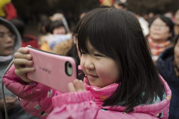 A girl with a smartphone in Beijing on Feb. 17, 2018.<br/>(Nicolas Asfouri/AFP/Getty Images)