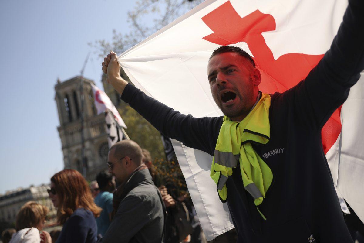 A man waves a flag near the Notre Dame Cathedral as he takes part in a yellow vest demonstration in Paris, on April 20, 2019. (Francisco Seco/AP Photo)