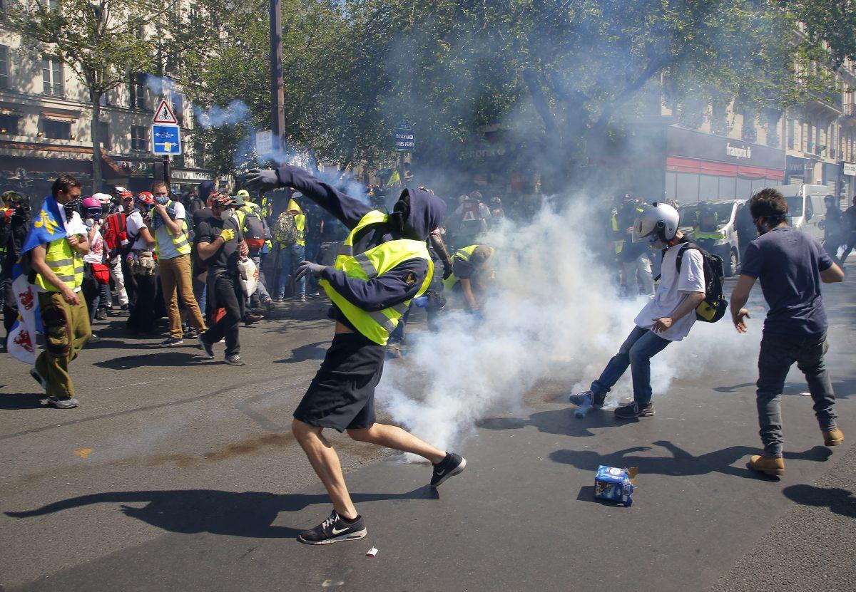 A demonstrator throws back a tear gas canister during a yellow vest demonstration in Paris, on April 20, 2019. (Michel Euler/AP Photo)