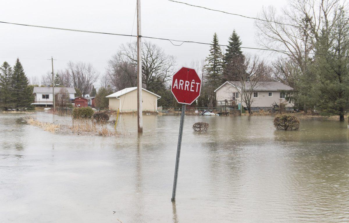 A residential street is shown surrounded by floodwaters in the town of Rigaud, Que. west of Montreal, on April 19, 2019. (Graham Hughes/The Canadian Press)