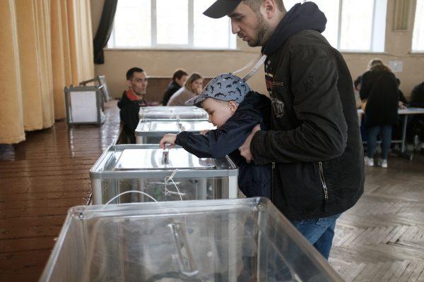 A man votes with his son in Kiev, Ukraine, during the second round of Ukraine’s presidential election on April 21, 2019. (Chris Collison for The Epoch Times)