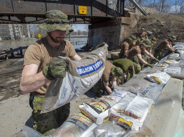 Canadian Forces personnel reinforce a dike against the rising floodwaters in Laval, Que., on April 21, 2019. (The Canadian Press/Ryan Remiorz)