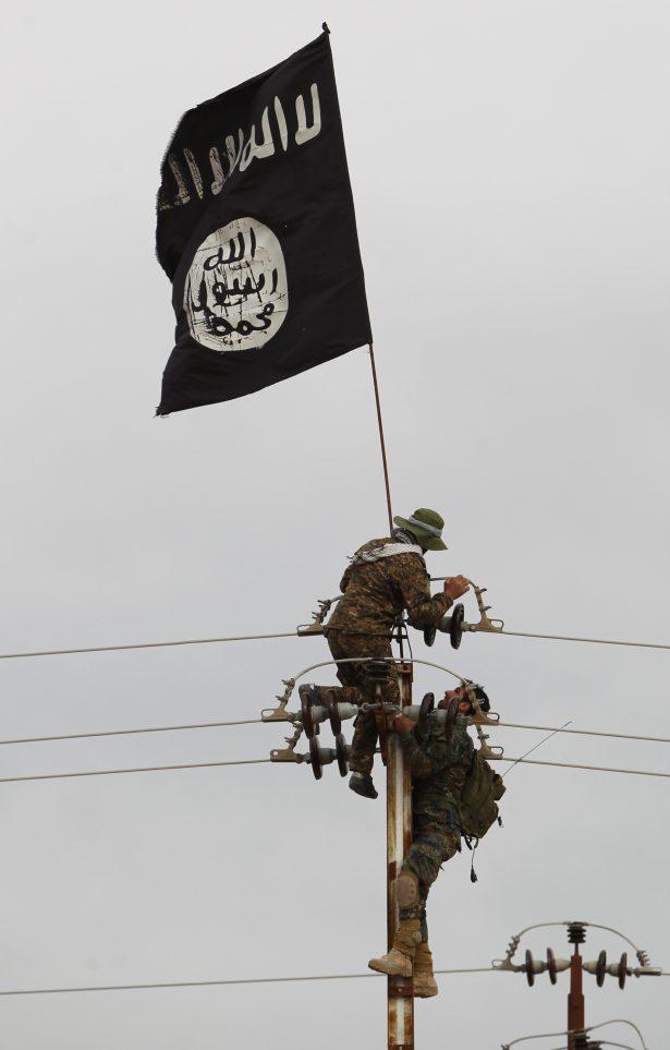 Iraqi Shiite fighters from the Popular Mobilization units take off an ISIS flag from an electricity pole on March 3, 2016, during an operation in the desert of Samarra aimed at retaking areas from ISIS jihadis. (Ahmad al-Rubaye/AFP/Getty Images)