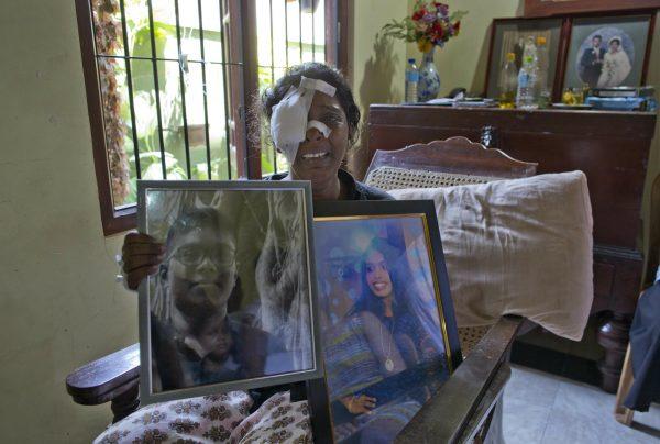 Anusha Kumari holds portraits of her daughter Sajini Venura Dulakshi and son Vimukthi Tharidu Appuhami, both victims of Easter Sunday's bomb blast in Negombo, Sri Lanka, April 24, 2019. (AP Photo/Gemunu Amarasinghe)