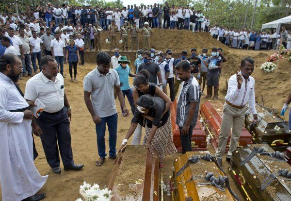 Anusha Kumari, center, holds a coffin during a mass burial for her husband, two children and three siblings, all victims of Easter Sunday's bomb blast in Negombo, Sri Lanka, on April 24, 2019. (Gemunu Amarasinghe/AP Photo)