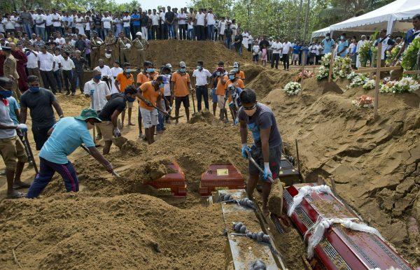 Workers bury coffins during a mass funeral for Easter Sunday bomb blast victims in Negombo, Sri Lanka, on April 24, 2019. (Gemunu Amarasinghe/Photo via AP)