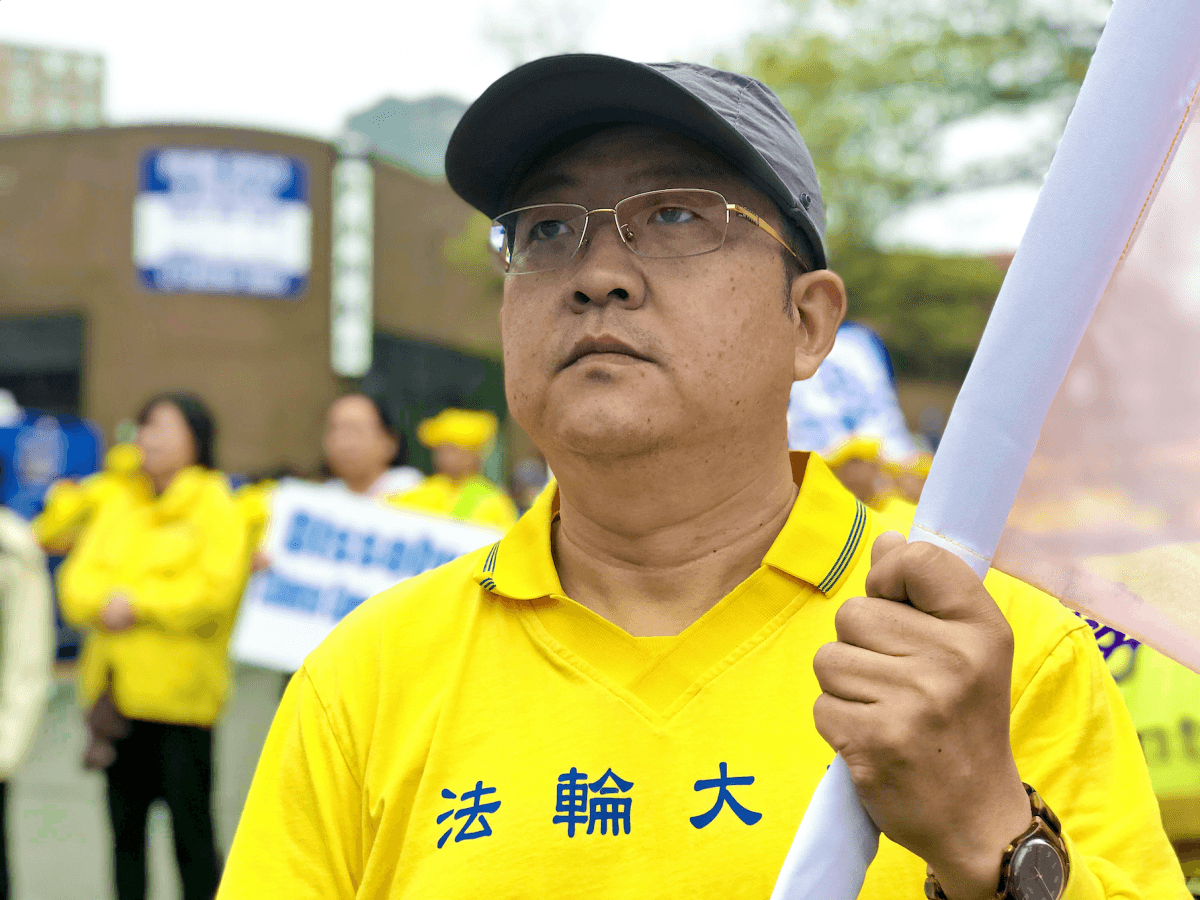 Pan Jun holds a banner at a rally in Flushing, New York City, on April 20 commemorating the upcoming 20th anniversary of a peaceful demonstration by Falun Gong practitioners in Beijing, China. (Stefania Cox/The Epoch Times)