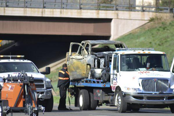 A tow truck driver removes a burnt-out car at the scene of a fiery crash on I-70 near Colorado Mills Parkway that shut down the highway in both directions on Friday, April 26, 2019, in Lakewood, Colo. (Peter Banda/AP Photo)