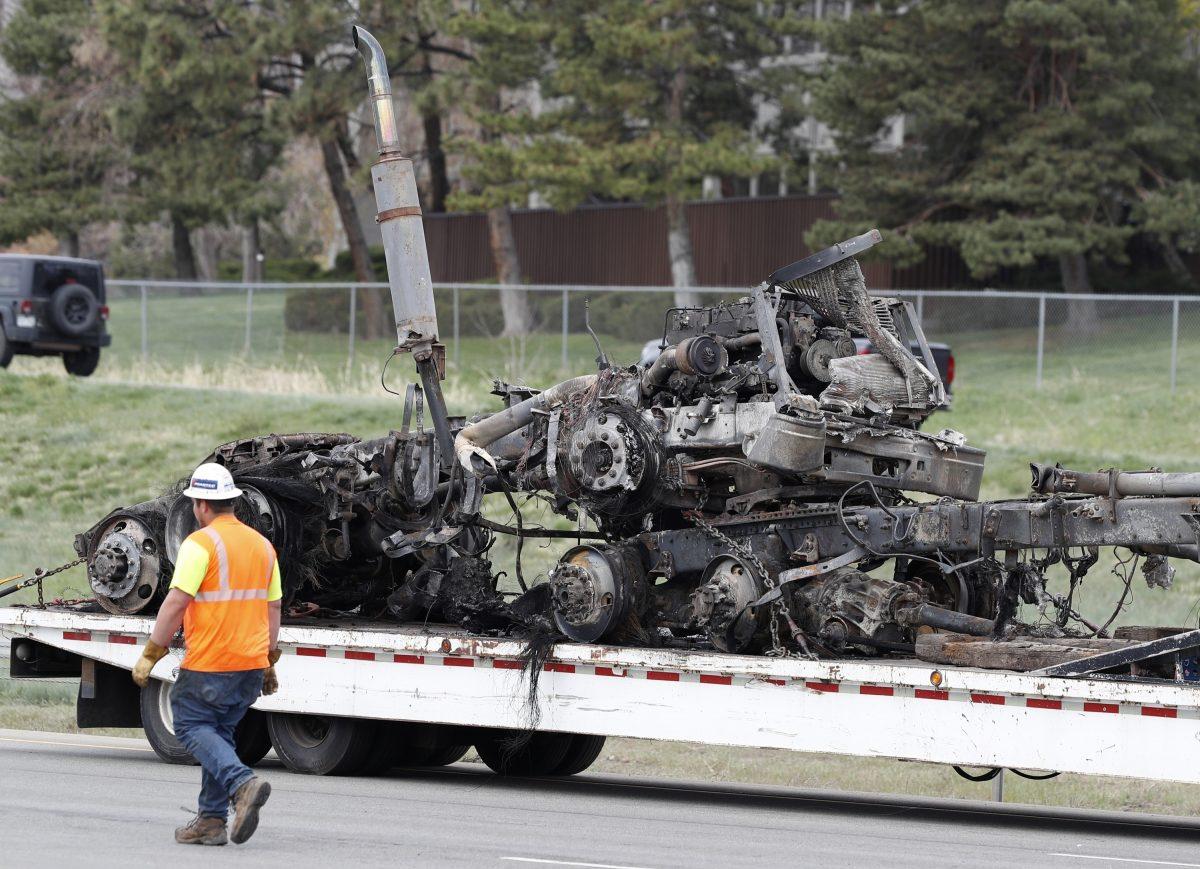 Workers clear debris, including the burned out section of a semi-truck, from Interstate 70 on April 26, 2019, in Lakewood, Colo., after a deadly pileup on Thursday. (AP Photo/David Zalubowski)