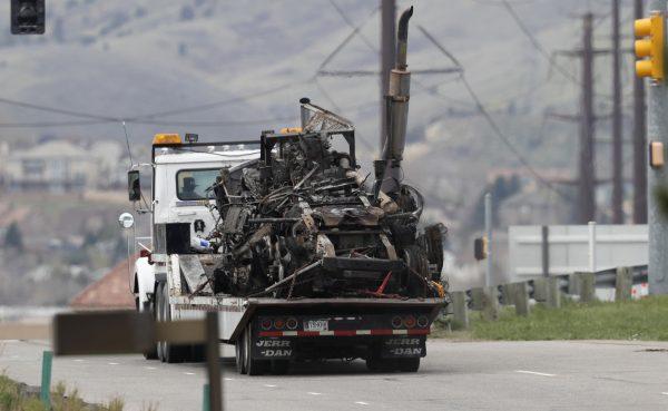 What remains of a semi-tractor and trailer are carried away as workers clear debris from the eastbound lanes of Interstate 70 on Friday, April 26, 2019, in Lakewood, Colo., after a deadly pileup involving semi-truck hauling lumber on April 25, 2019. (David Zalubowski/AP Photo)