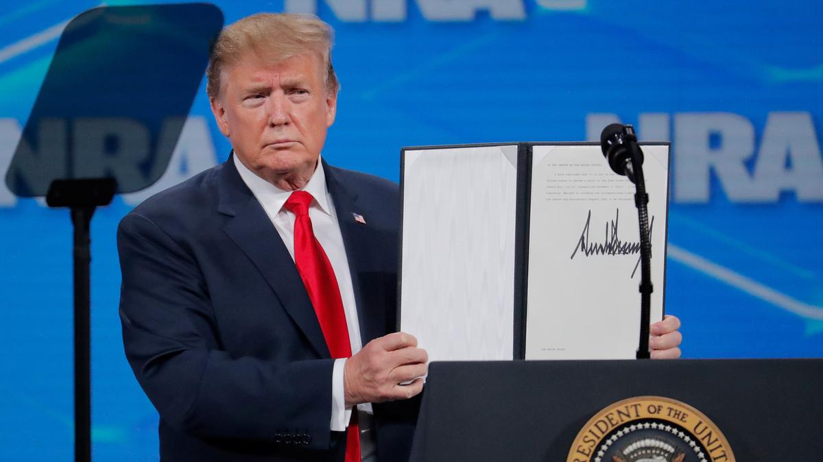 President Trump holds up an executive order he signed at an NRA event on April 26, announcing that the United States will drop out of an international arms trade treaty that was signed during the Obama administration. (Lucas Jackson/Reuters)