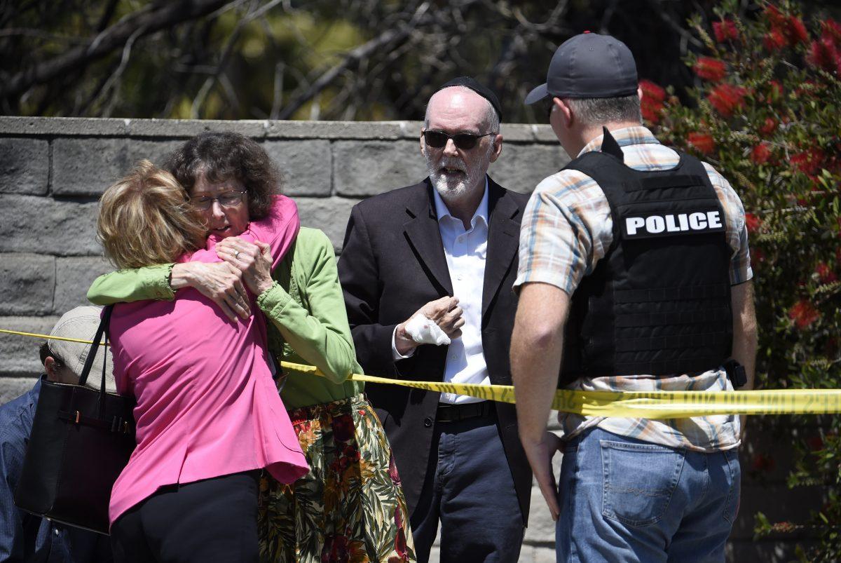 Two people hug as another talks to a San Diego County Sheriff's deputy outside of the Chabad of Poway Synagogue in Poway, Calif., on April 27, 2019. (Denis Poroy/AP Photo)