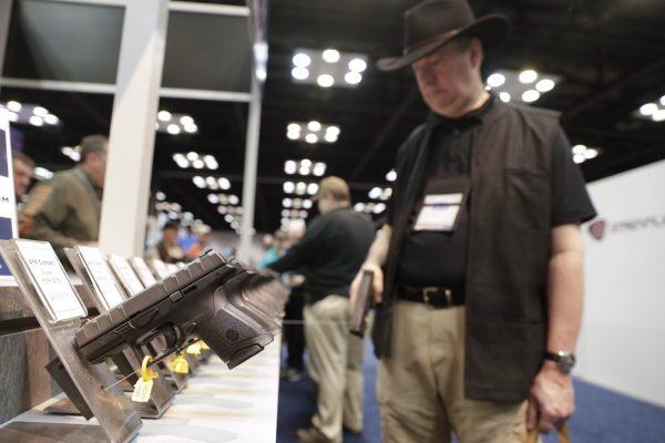 A gun enthusiast looks over the display of Beretta pistols on display in the exhibition hall at the National Rifle Association Annual Meeting in Indianapolis, on April 27, 2019. (Michael Conroy/AP Photo)