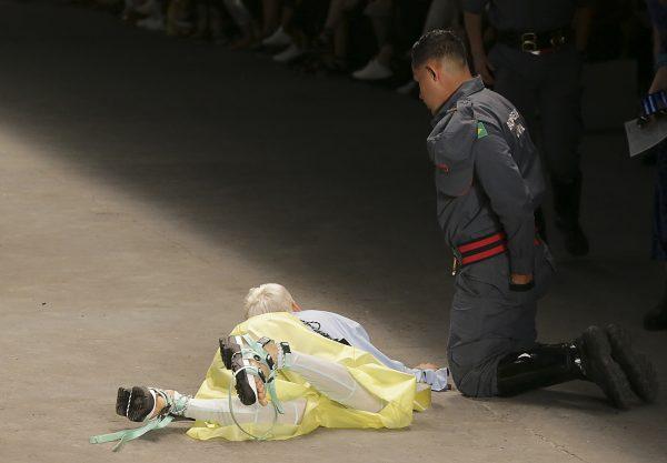 Model Tales Soares lies on the catwalk as a paramedic tends to him after he collapsed during Sao Paulo Fashion Week in Sao Paulo, Brazil, in April 27, 2019. (Leco Viana/Thenews2 via AP)
