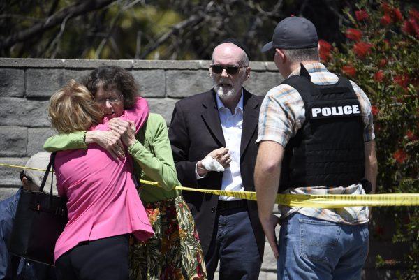 Two people hug as another talks to a San Diego County Sheriff's deputy outside of the Chabad of Poway synagogue in Poway, Calif., on April 27, 2019. (Denis Poroy/Photo via AP)