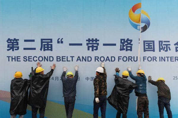 Workers take down a Belt and Road forum panel outside the venue in Beijing on April 27, 2019. (Greg Baker/AFP/Getty Images)